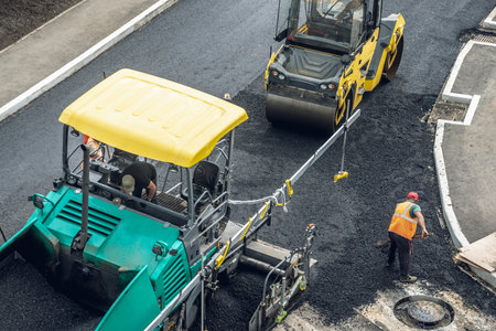 Workers lay a new asphalt coating using hot bitumen. Work of heavy machinery and paver. The view from the topの写真素材