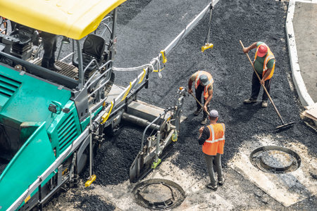 Workers lay a new asphalt coating using hot bitumen. Work of heavy machinery and paver. The view from the topの写真素材