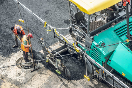 Workers lay a new asphalt coating using hot bitumen. Work of heavy machinery and paver. The view from the topの写真素材