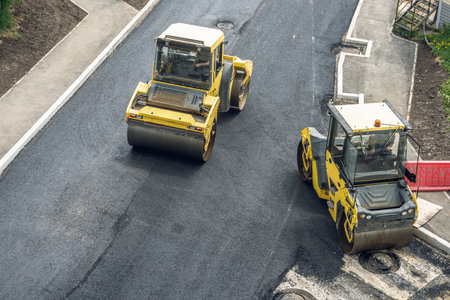 Workers lay a new asphalt coating using hot bitumen. Work of heavy machinery and paver. The view from the topの写真素材