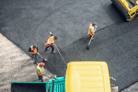 Workers lay a new asphalt coating using hot bitumen. Work of heavy machinery and paver. The view from the topの写真素材