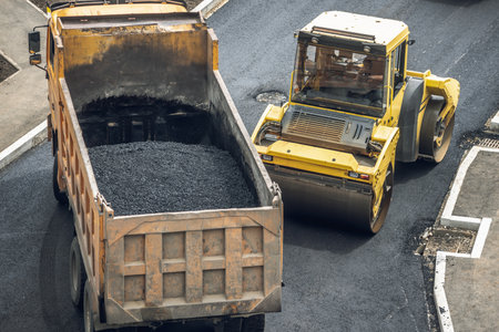 Workers lay a new asphalt coating using hot bitumen. Work of heavy machinery and paver. The view from the topの写真素材