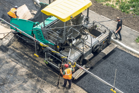 Workers lay a new asphalt coating using hot bitumen. Work of heavy machinery and paver. The view from the topの写真素材