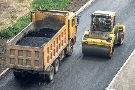 Workers lay a new asphalt coating using hot bitumen. Work of heavy machinery and paver. The view from the topの写真素材