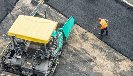Workers lay a new asphalt coating using hot bitumen. Work of heavy machinery and paver. The view from the topの写真素材