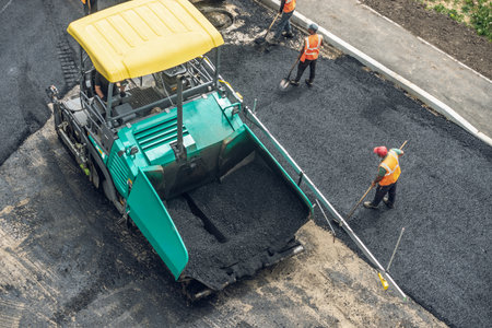 Workers lay a new asphalt coating using hot bitumen. Work of heavy machinery and paver. The view from the topの写真素材