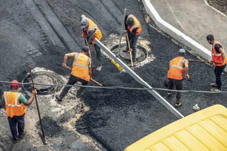 Workers lay a new asphalt coating using hot bitumen. Work of heavy machinery and paver. The view from the topの写真素材