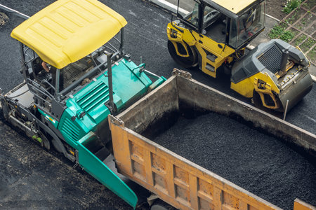 Workers lay a new asphalt coating using hot bitumen. Work of heavy machinery and paver. The view from the topの写真素材