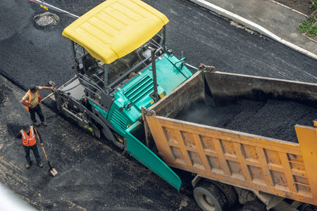 Workers lay a new asphalt coating using hot bitumen. Work of heavy machinery and paver. The view from the topの写真素材