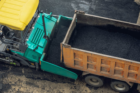 Workers lay a new asphalt coating using hot bitumen. Work of heavy machinery and paver. The view from the topの写真素材