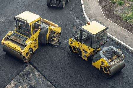 Workers lay a new asphalt coating using hot bitumen. Work of heavy machinery and paver. The view from the topの写真素材