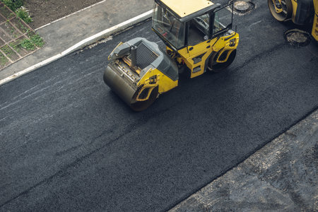 Workers lay a new asphalt coating using hot bitumen. Work of heavy machinery and paver. The view from the topの写真素材