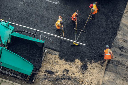 Workers lay a new asphalt coating using hot bitumen. Work of heavy machinery and paver. The view from the topの写真素材