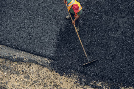 Workers lay a new asphalt coating using hot bitumen. Work of heavy machinery and paver. The view from the topの写真素材