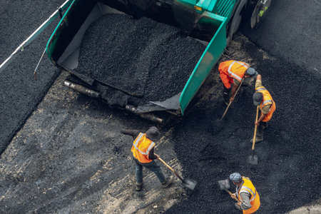 Workers lay a new asphalt coating using hot bitumen. Work of heavy machinery and paver. The view from the topの写真素材