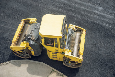 Workers lay a new asphalt coating using hot bitumen. Work of heavy machinery and paver. The view from the topの写真素材