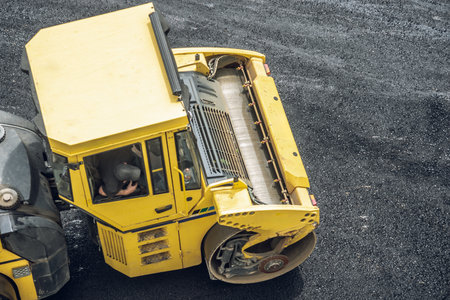 Workers lay a new asphalt coating using hot bitumen. Work of heavy machinery and paver. The view from the topの写真素材
