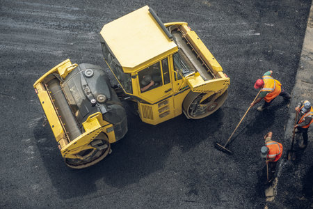 Workers lay a new asphalt coating using hot bitumen. Work of heavy machinery and paver. The view from the topの写真素材