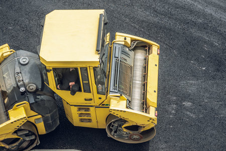 Workers lay a new asphalt coating using hot bitumen. Work of heavy machinery and paver. The view from the topの写真素材