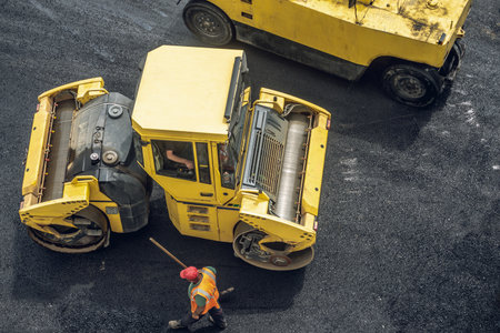 Workers lay a new asphalt coating using hot bitumen. Work of heavy machinery and paver. The view from the topの写真素材