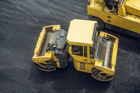 Workers lay a new asphalt coating using hot bitumen. Work of heavy machinery and paver. The view from the topの写真素材