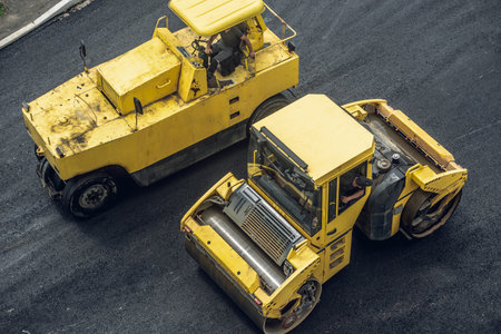 Workers lay a new asphalt coating using hot bitumen. Work of heavy machinery and paver. The view from the topの写真素材