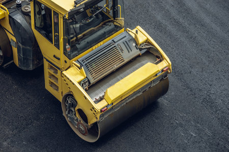 Workers lay a new asphalt coating using hot bitumen. Work of heavy machinery and paver. The view from the topの写真素材