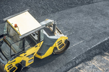 Workers lay a new asphalt coating using hot bitumen. Work of heavy machinery and paver. The view from the topの写真素材