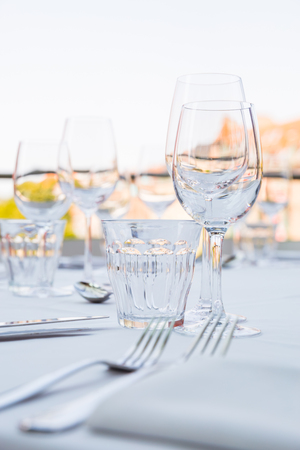 Empty glasses on a table covered with a white tableclothの写真素材
