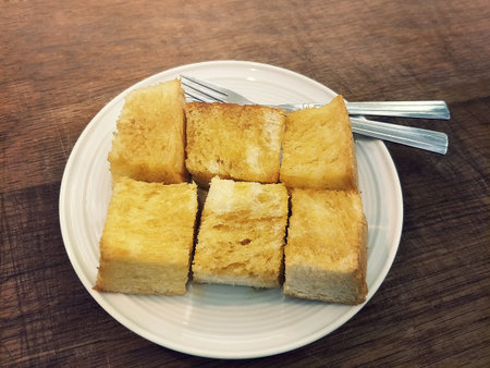 butter toast cut in piece topped with honey caramel served on white dish with fork