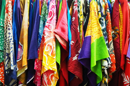 row of assorted colorful asian batik shirts at market displayの写真素材