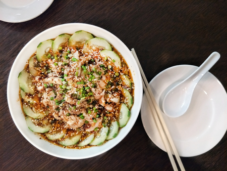 chinese dish - Kou Shui Ji; steamed Chicken in Sichuan pepper Chili Oil Sauce surround by cucumber served on white bowl eat with steamed rice photo taken from top viewの素材 [FY310102564301]