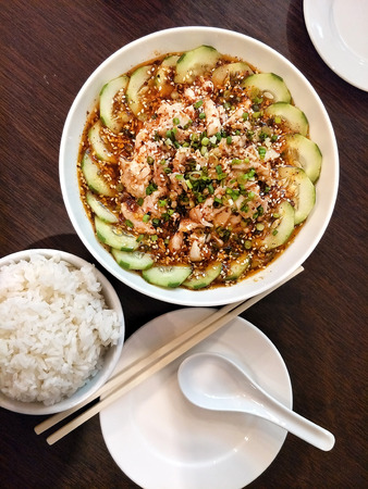 chinese dish - Kou Shui Ji; steamed Chicken in Sichuan pepper Chili Oil Sauce surround by cucumber served on white bowl eat with steamed rice photo taken from top viewの写真素材