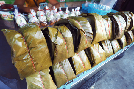 Tradition Local Northern Thailand food for sale at food stall on the street in Chiang Mai called "Khao Jin Moo" is the steamed rice with mince pork and pig blood wrapped with banana leafの写真素材