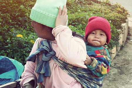 CHIANG MAI THAILAND - 30 January 2018: Local Mountain Hmong tribal girl carrying kid that looking at the camera on the her back at Doi Ang Khang, Fang, Chiang Mai, Thailandのeditorial素材
