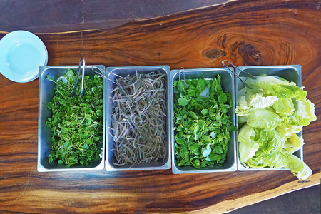 raw fresh vegetable in big stainless tray lack inside local thai buffet restaurant for customer served on wooden table photo taken from above top viewの写真素材