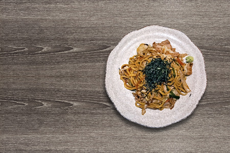 japanese style fry noodle called Yakisoba served on ceramic stone plate dish on wooden table texture view from above topの写真素材