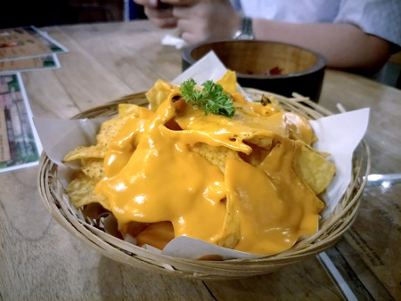 nachos topped with cheease in restaurant environment and people on backgroundの写真素材