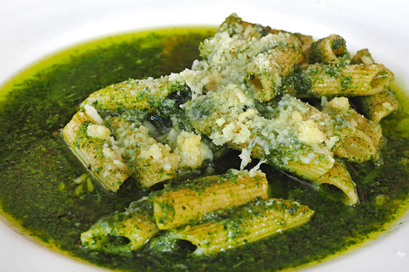 macaroni in full load of green basil pesto sauce close up macro photoの写真素材