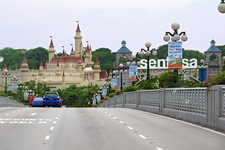 Singapore - 15 MAY 2011: car cross over bridge to Entrance Sentosa Island with big sign at front and beautiful palace on backgroundのeditorial素材