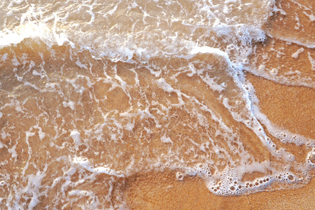 Close up photo from top view of wave foam coming to the beachの写真素材
