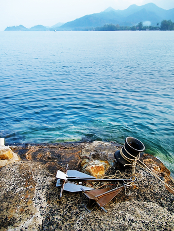 anchor rope on the rock on ocean beach with blue clear water and mountain backgroundの写真素材