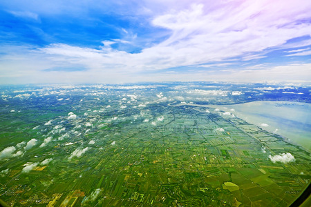 aerial view of grass field farm with city village and cloudy blue sky photo shoot from airplane windowの写真素材