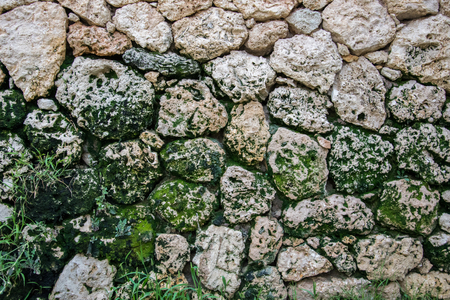 wall texture of old stone rock green moss backgroundの写真素材