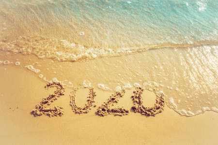 Happy New Year 2020 concept, 2020 number lettering on the sea beach, wave and golden light of sunset.の写真素材
