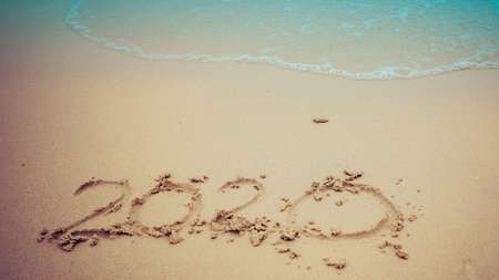 Happy New Year 2020 concept, 2020 number lettering on the sea beach, wave and golden light of sunset.の写真素材