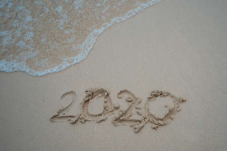 Happy New Year 2020 concept, 2020 number lettering on the sea beach, wave and golden light of sunset.の写真素材