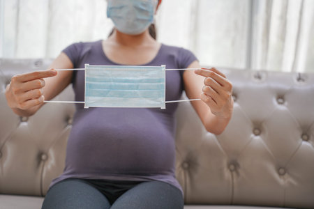 A pregnant woman wears a surgical mask to protect a COVID-19 (Coronavirus) and PM 2.5 and show a...