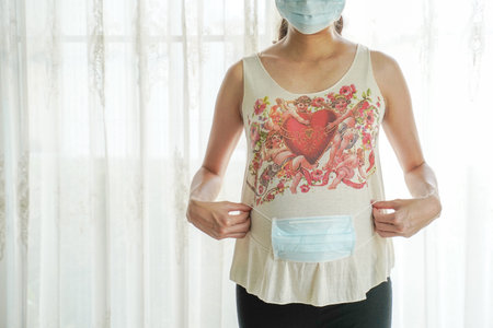 A pregnant woman wears a surgical mask to protect a COVID-19 (Coronavirus) and PM 2.5 and show a...