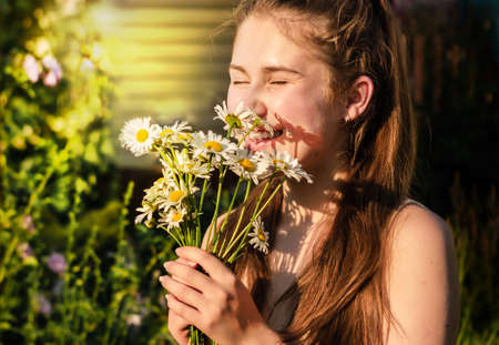 A young girl holds a bouquet of flowers in her hands and laughs happily, a selective focusの写真素材